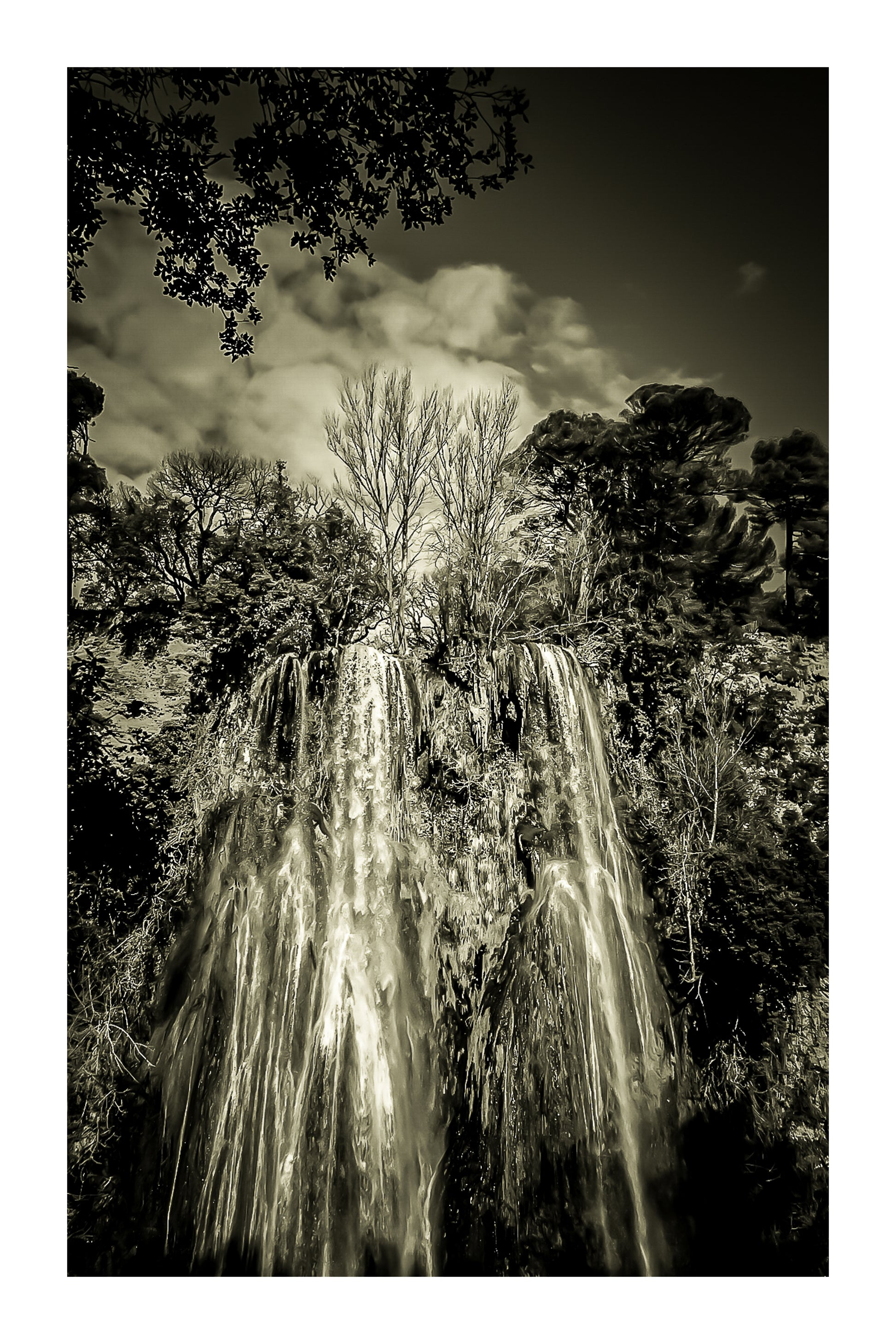 Haute cascade de Sillans se détachant sur un ciel bleu, encadrée par les arbres de la forêt, vintage avec bordure