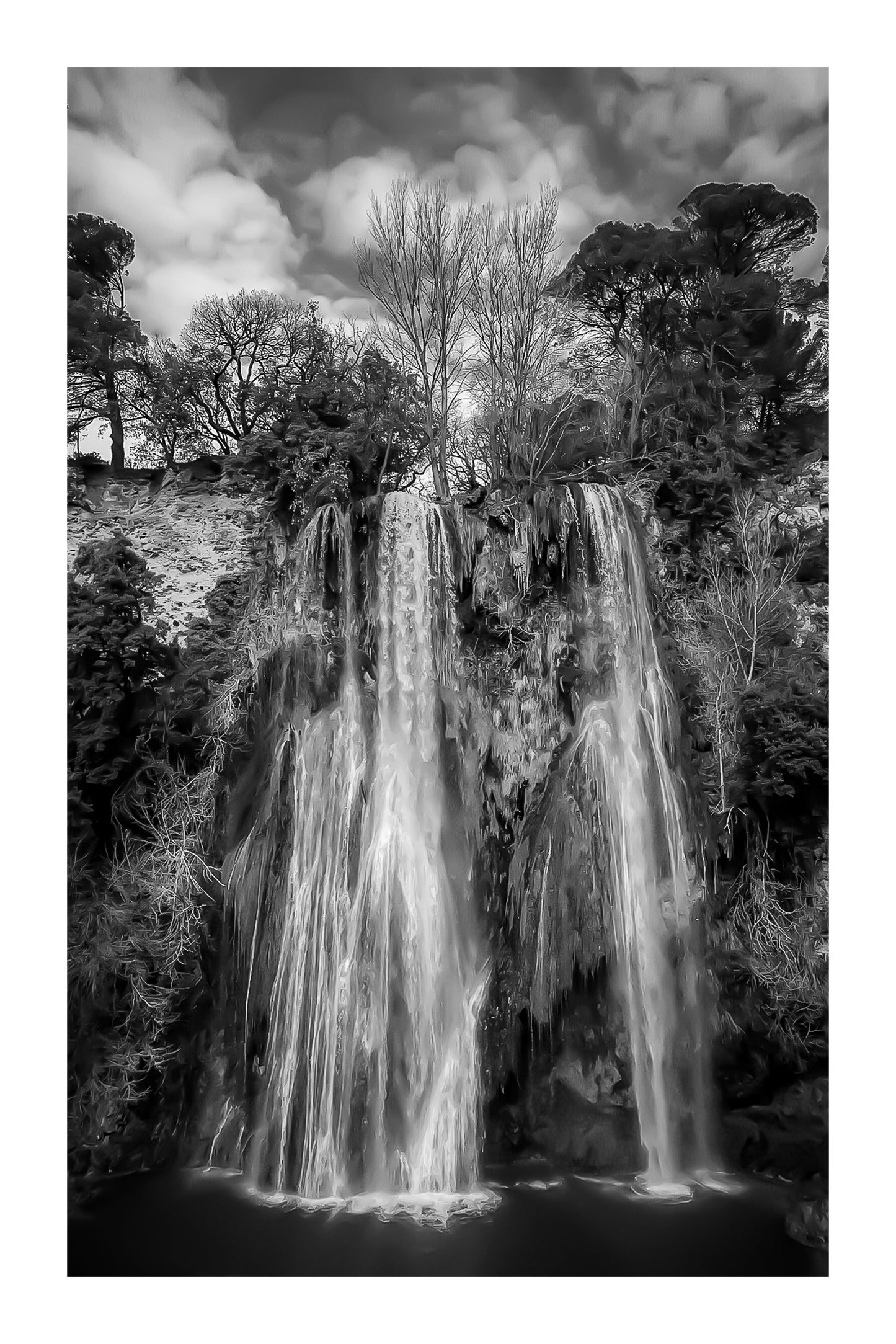 Grande cascade de Sillans se jetant dans un bassin vert émeraude entouré de falaises et de végétation, noir et blanc avec bordure