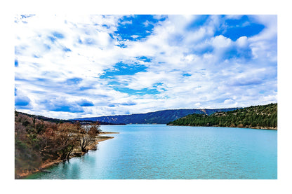 Large vue sur le lac de Sainte-Croix depuis un pont, rives boisées et grand ciel nuageux avec bordure