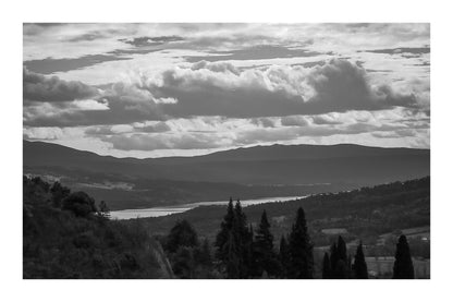 Vue lointaine sur le lac de Sainte-Croix entouré de collines, sous un ciel de nuages contrastés, noir et blanc avec bordure