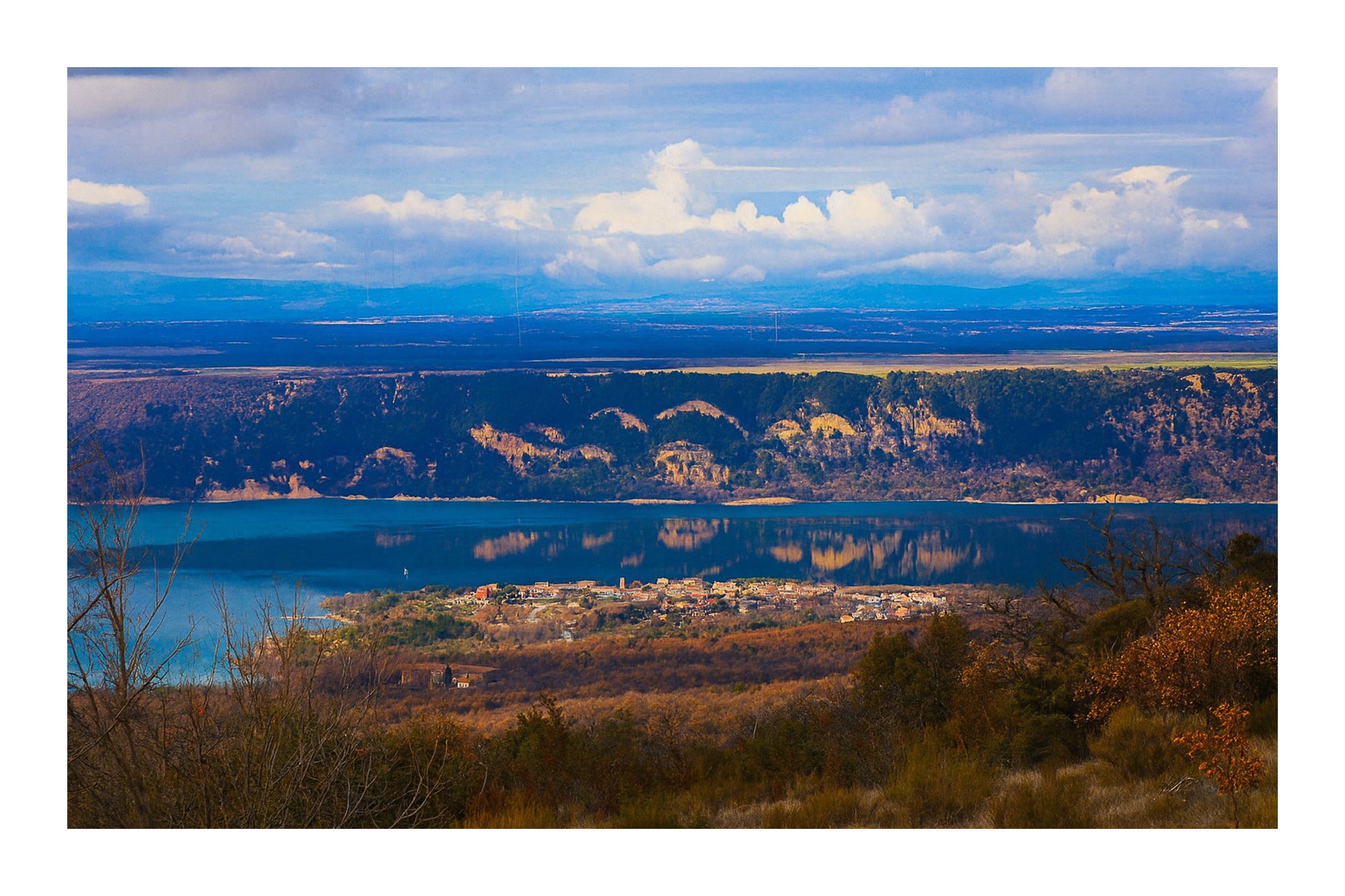 Village provençal posé au bord du lac de Sainte-Croix, falaises et reflets dorés sur l’eau calme avec bordure