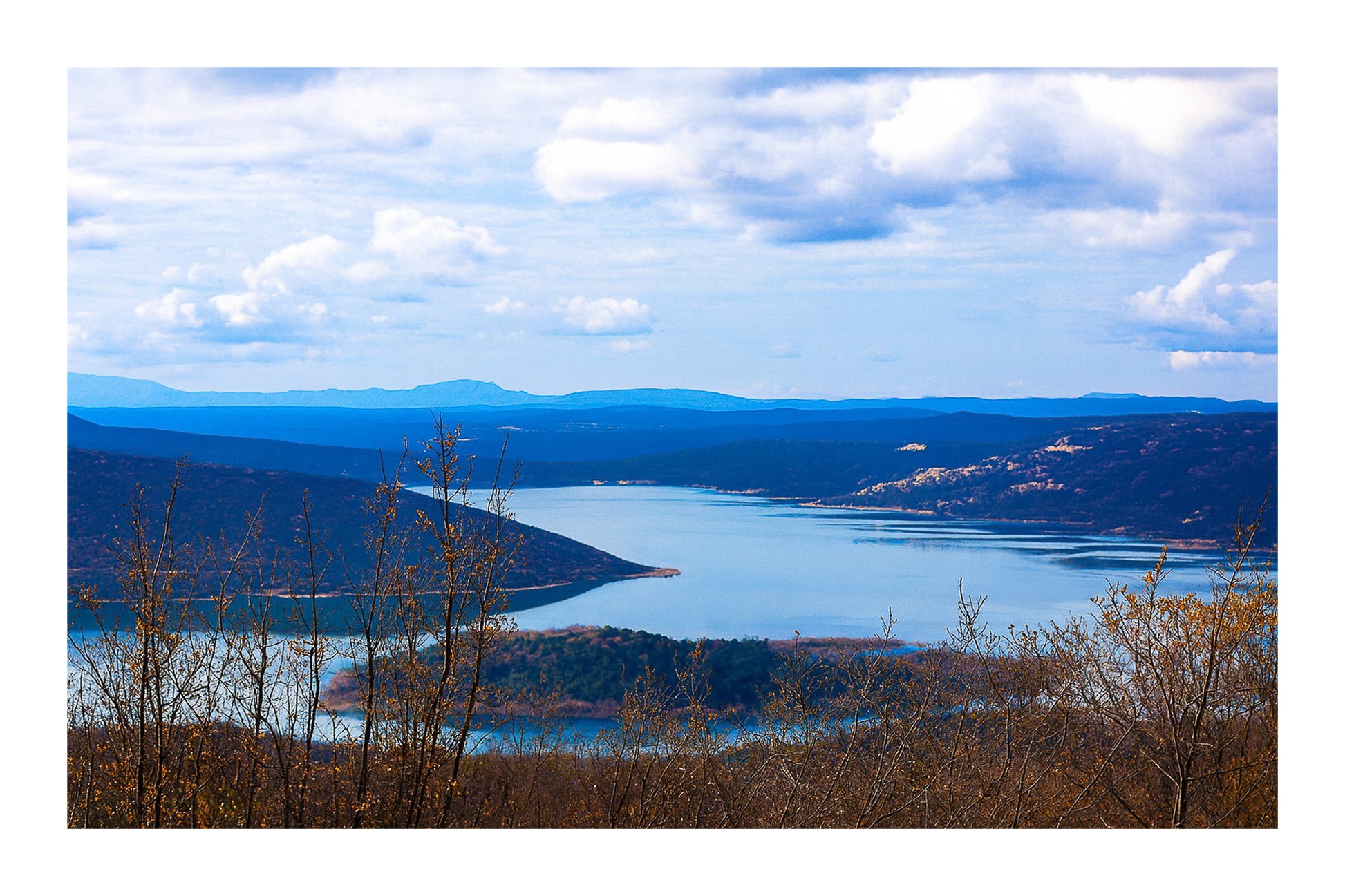 Long bras du lac de Sainte-Croix s’étirant entre collines et bosquets, sous un ciel nuageux avec bordure