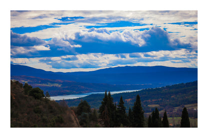Vue lointaine sur le lac de Sainte-Croix entouré de collines, sous un ciel de nuages contrastés avec bordure