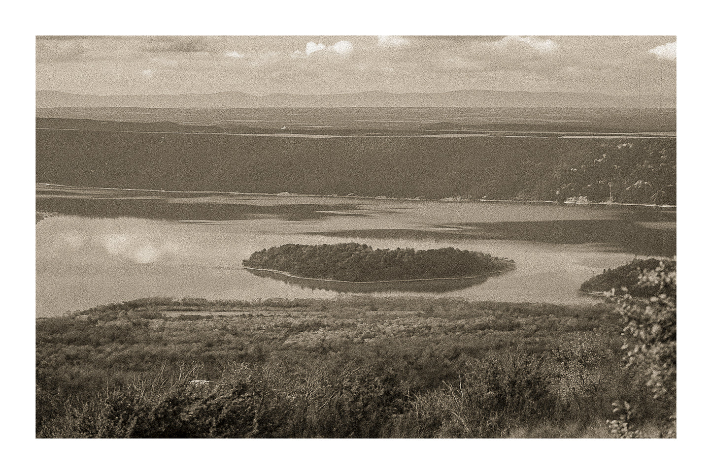 Îlot boisé flottant au centre du lac de Sainte-Croix, eaux calmes et reliefs sombres en arrière-plan, vintage avec bordure