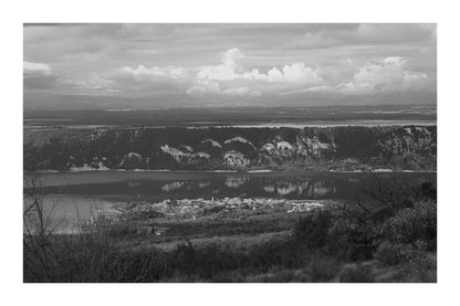 Village provençal posé au bord du lac de Sainte-Croix, falaises et reflets dorés sur l’eau calme, noir et blanc avec bordure