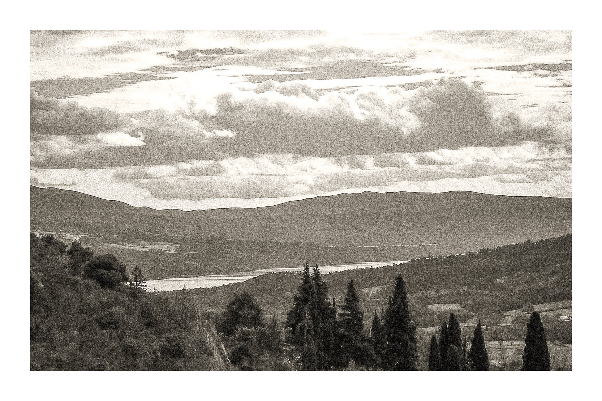 Vue lointaine sur le lac de Sainte-Croix entouré de collines, sous un ciel de nuages contrastés, vintage avec bordure