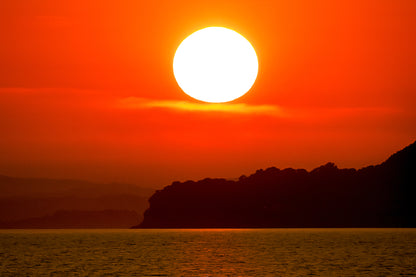 Gros soleil couchant orange au-dessus de la presqu’île de Giens vu depuis la plage de l’Almanarre
