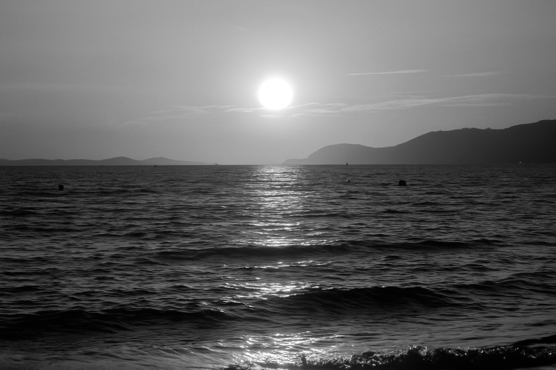 Coucher de soleil doré se reflétant sur la mer calme à la plage de l’Almanarre un soir d’été, noir et blanc