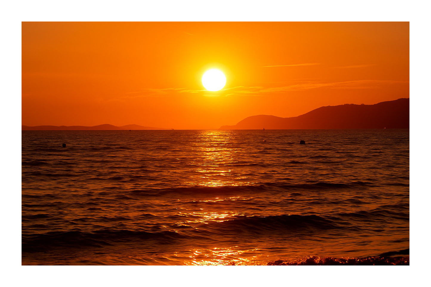 Coucher de soleil doré se reflétant sur la mer calme à la plage de l’Almanarre un soir d’été avec bordure