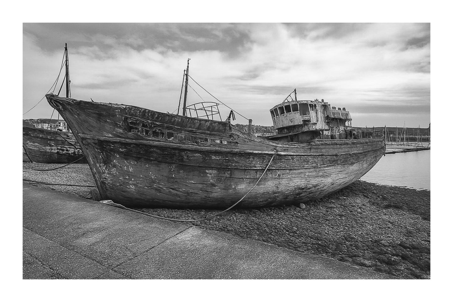 Grand chalutier rouillé échoué à marée basse, coque bleue écaillée, port de Camaret, noir et blanc avec bordure