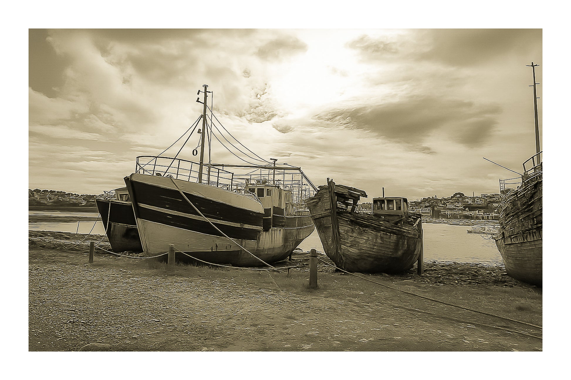 Bateau plus récent sur la gauche et coque déchiquetée à droite sur la grève de Camaret, ciel lumineux, vintage avec bordure