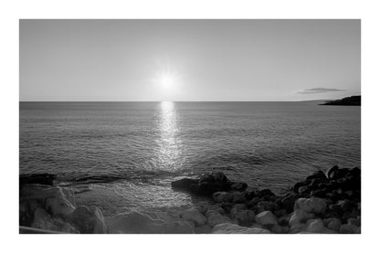 coucher de soleil à Carry-le-Rouet avec reflet doré sur la mer et premiers plans rocheux, noir et blanc avec bordure