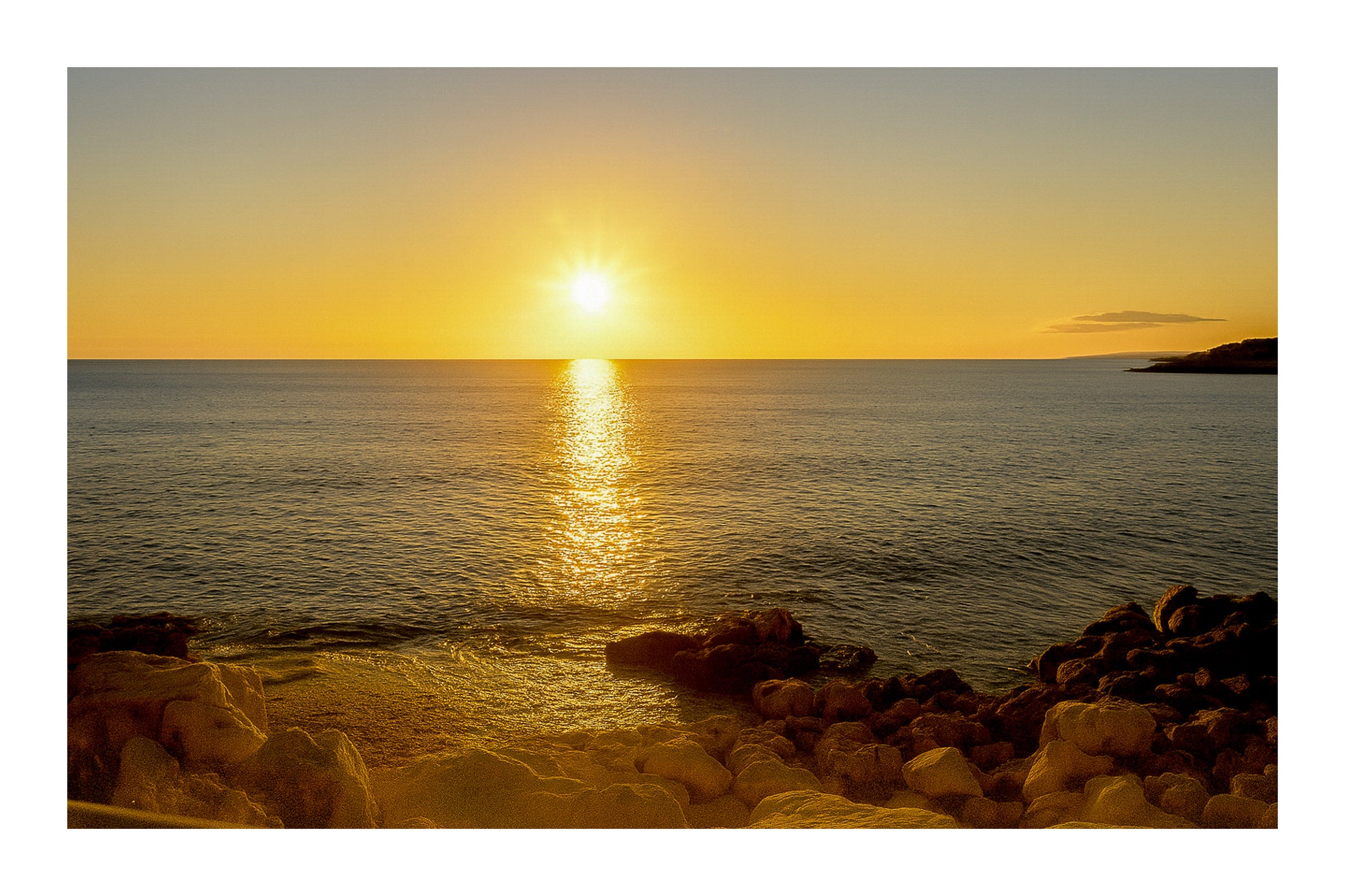 coucher de soleil à Carry-le-Rouet avec reflet doré sur la mer et premiers plans rocheux avec bordure