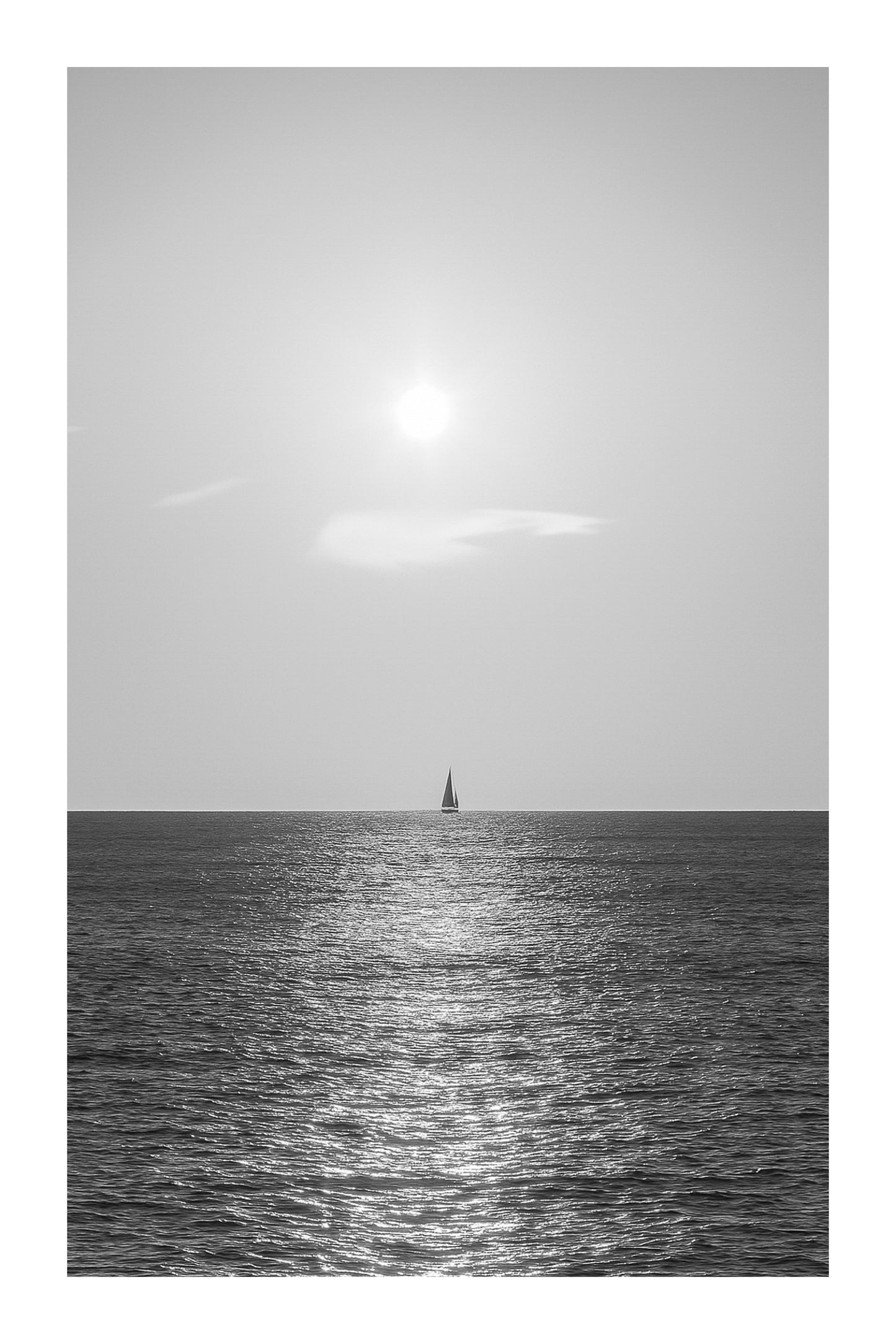 voilier solitaire naviguant dans le reflet du soleil couchant à Carry-le-Rouet format vertical, noir et blanc avec bordure