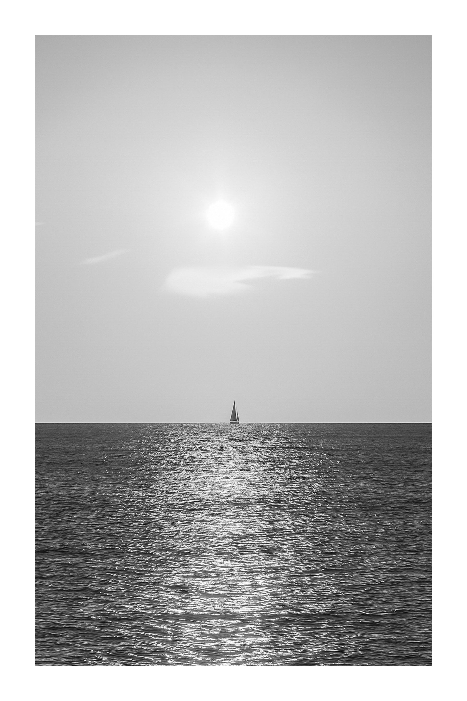voilier solitaire naviguant dans le reflet du soleil couchant à Carry-le-Rouet format vertical, noir et blanc avec bordure