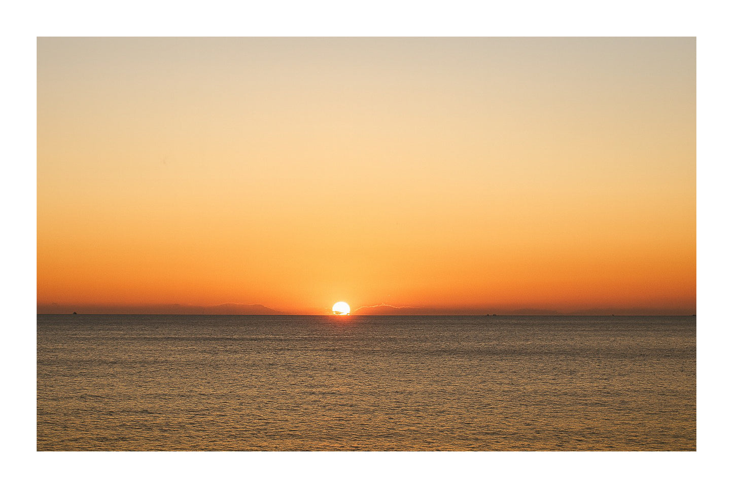 gros plan de l’astre couchant à l’horizon marin, ciel orange à Carry-le-Rouet, avec bordure