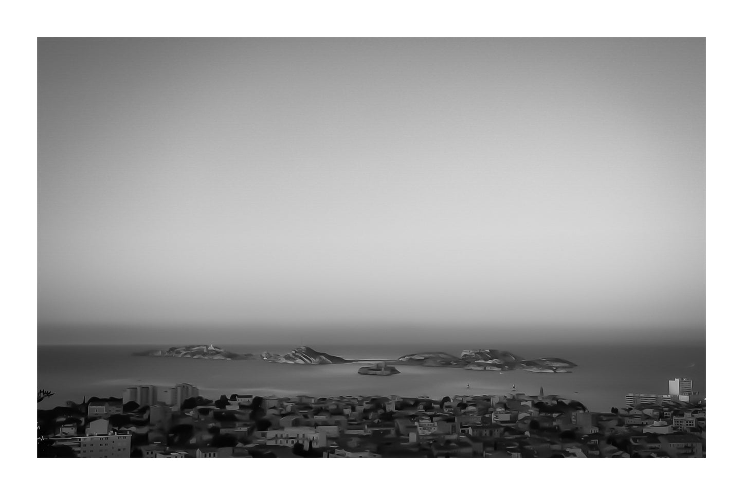 Panorama de Marseille avec les îles du Frioul et le Château d’If à l’horizon au soleil couchant, noir et blanc avec bordure