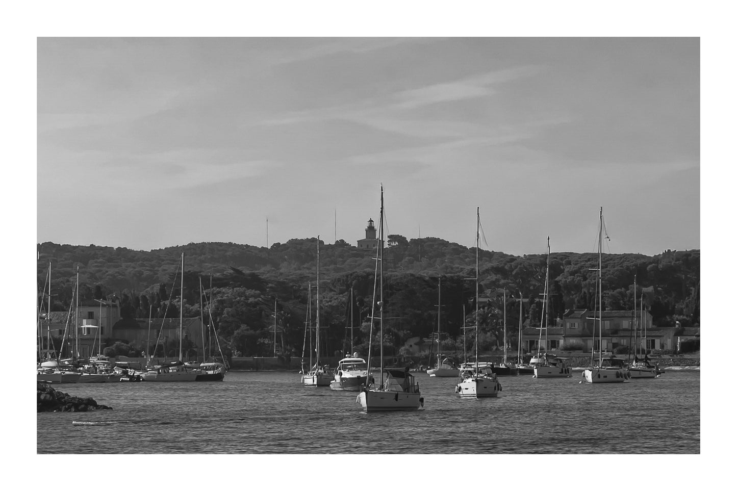 Voiliers au mouillage devant le village de Porquerolles avec le phare sur la colline, ciel bleu et pinède méditerranéenne, noir et blanc avec bordure