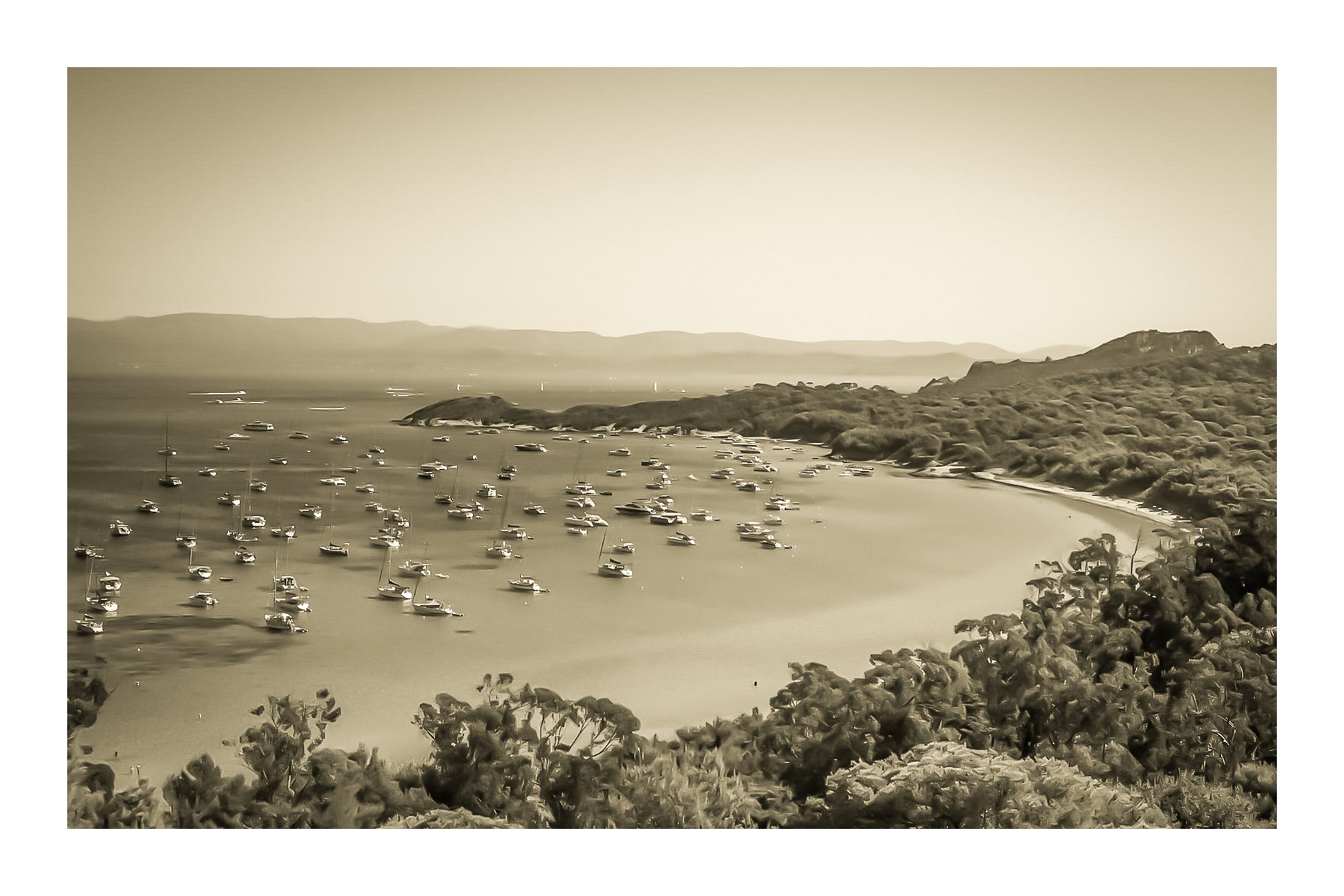 Vue plongeante sur la grande baie de Porquerolles avec de nombreux bateaux ancrés dans une eau turquoise sous un ciel d’été, vintage avec bordure