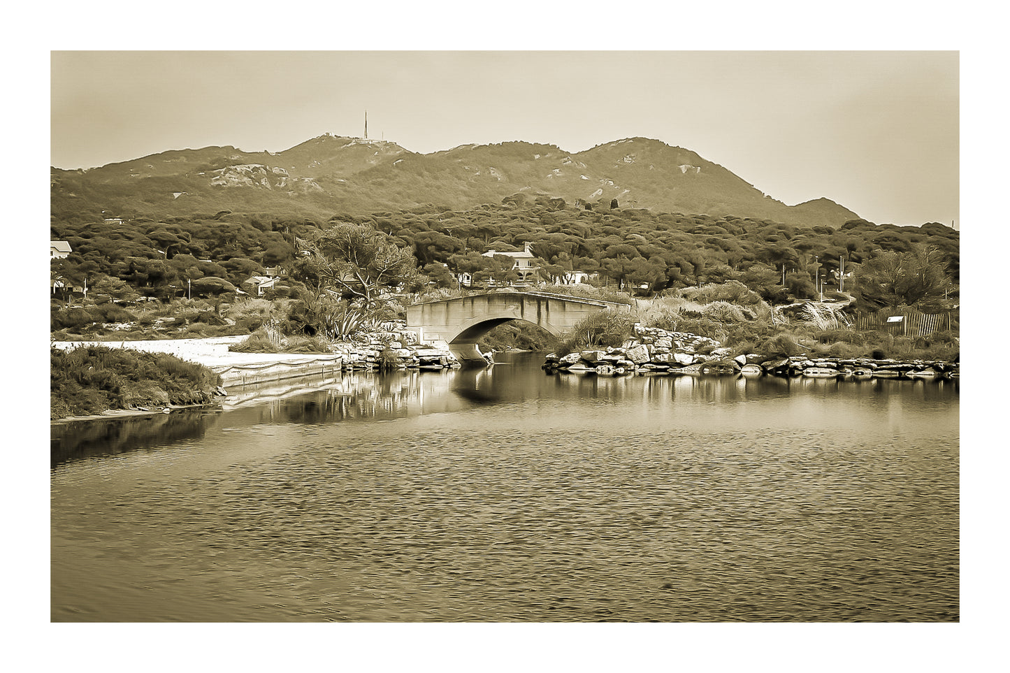 Petit pont en arc sur le canal intérieur des Embiez avec collines en arrière-plan, rendu sépia avec bordure
