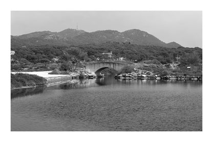 Petit pont en arc sur le canal intérieur des Embiez avec collines en arrière-plan, noir et blanc avec bordure