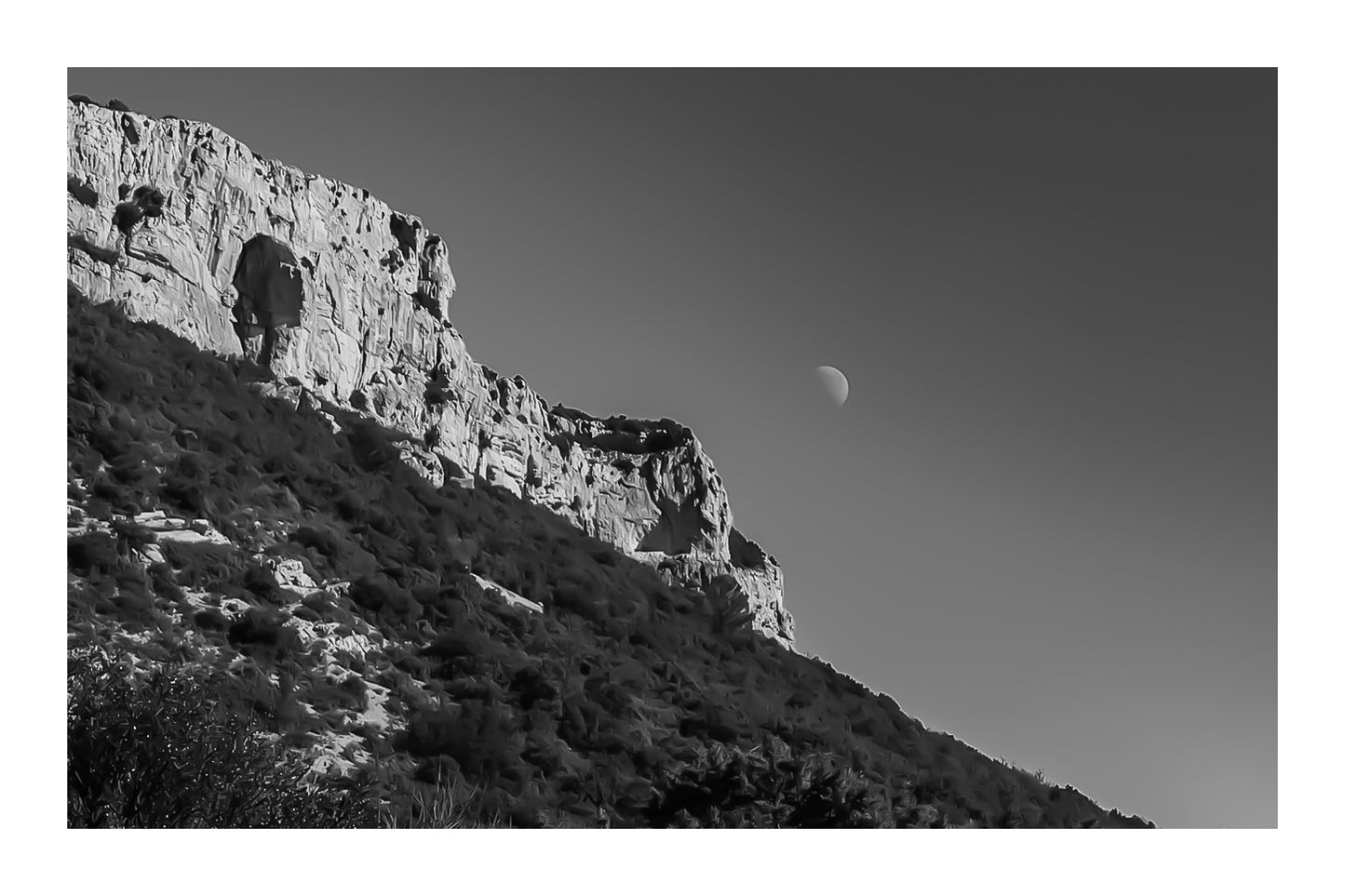 Paroi rocheuse de la Sainte-Baume et lune dans un ciel noir et blanc contrasté, ambiance graphique avec bordure