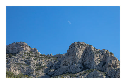 Demi-lune au-dessus des crêtes calcaires de Sugiton, ciel bleu profond et relief minéral, avec bordure
