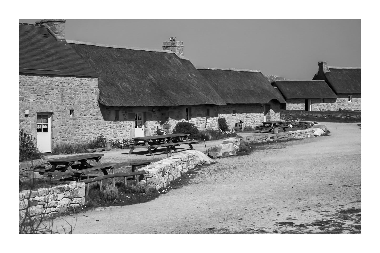 Longère de Meneham avec tables en bois, mur de pierre et toit de chaume, noir et blanc avec bordure - Kerlouan, Finistère, avec bordure