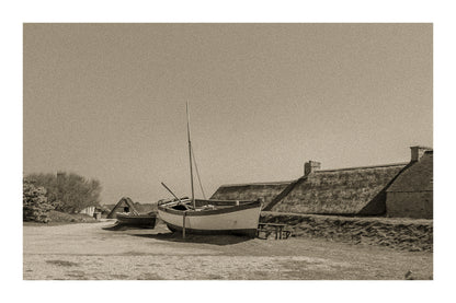 Barques tirées au sec devant les toits de chaume et murets de pierre à Meneham, ambiance ancienne en sépia avec bordure