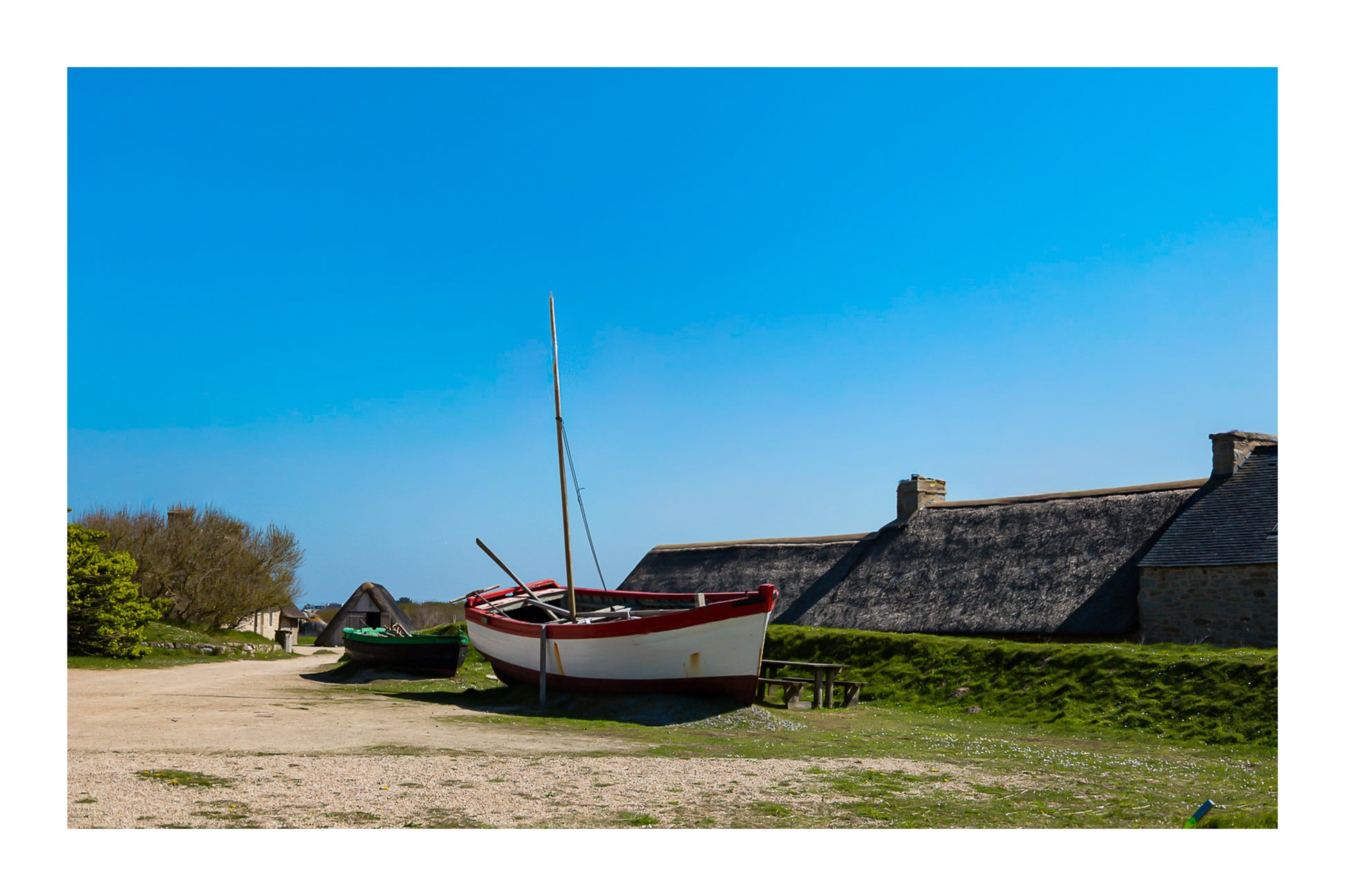 Barques tirées au sec devant les toits de chaume et murets de pierre à Meneham, ambiance ancienne, couleur avec bordure
