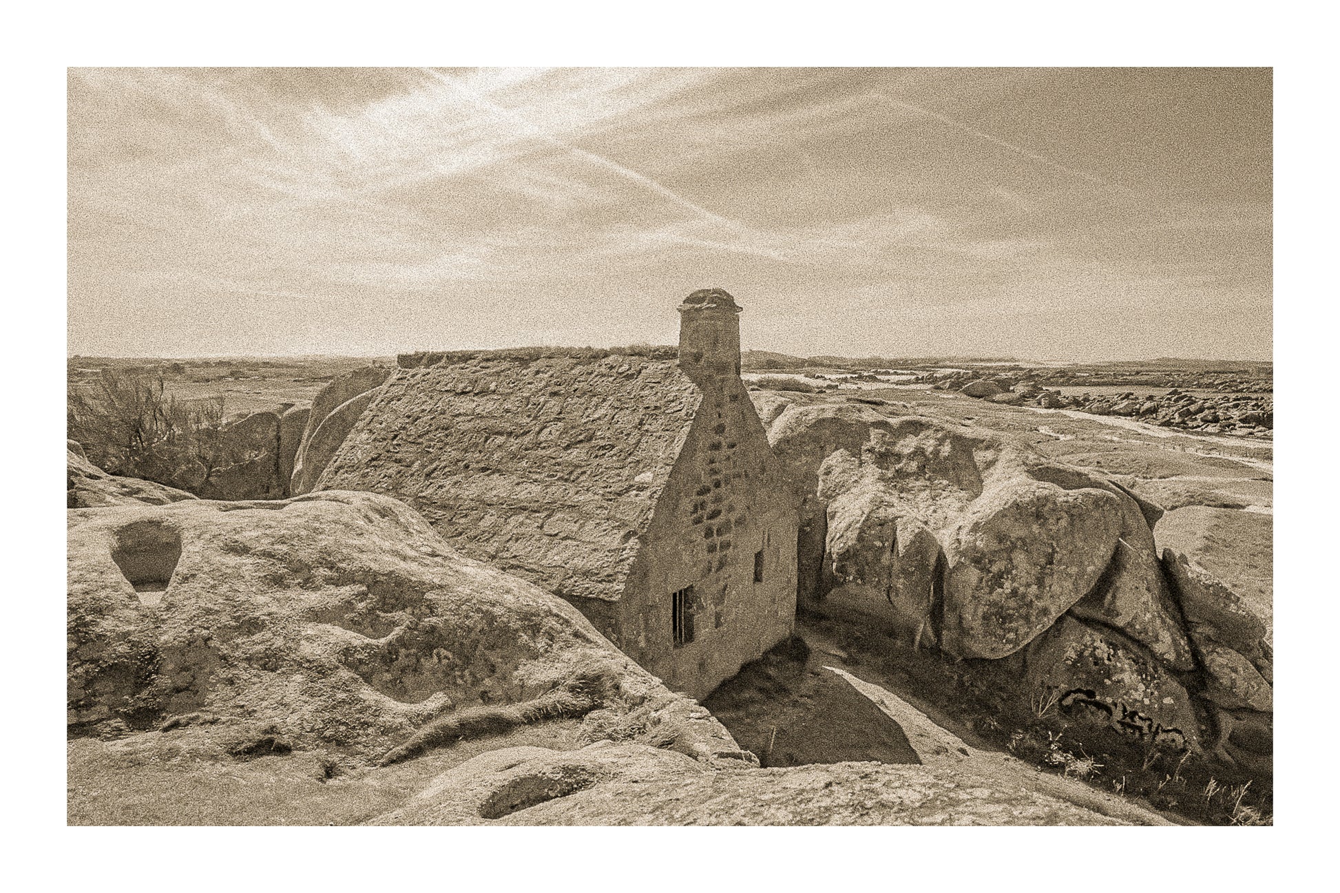 La maison emblématique de Meneham nichée entre deux énormes blocs de granit, vue d’ensemble en sépia vintage avec bordure