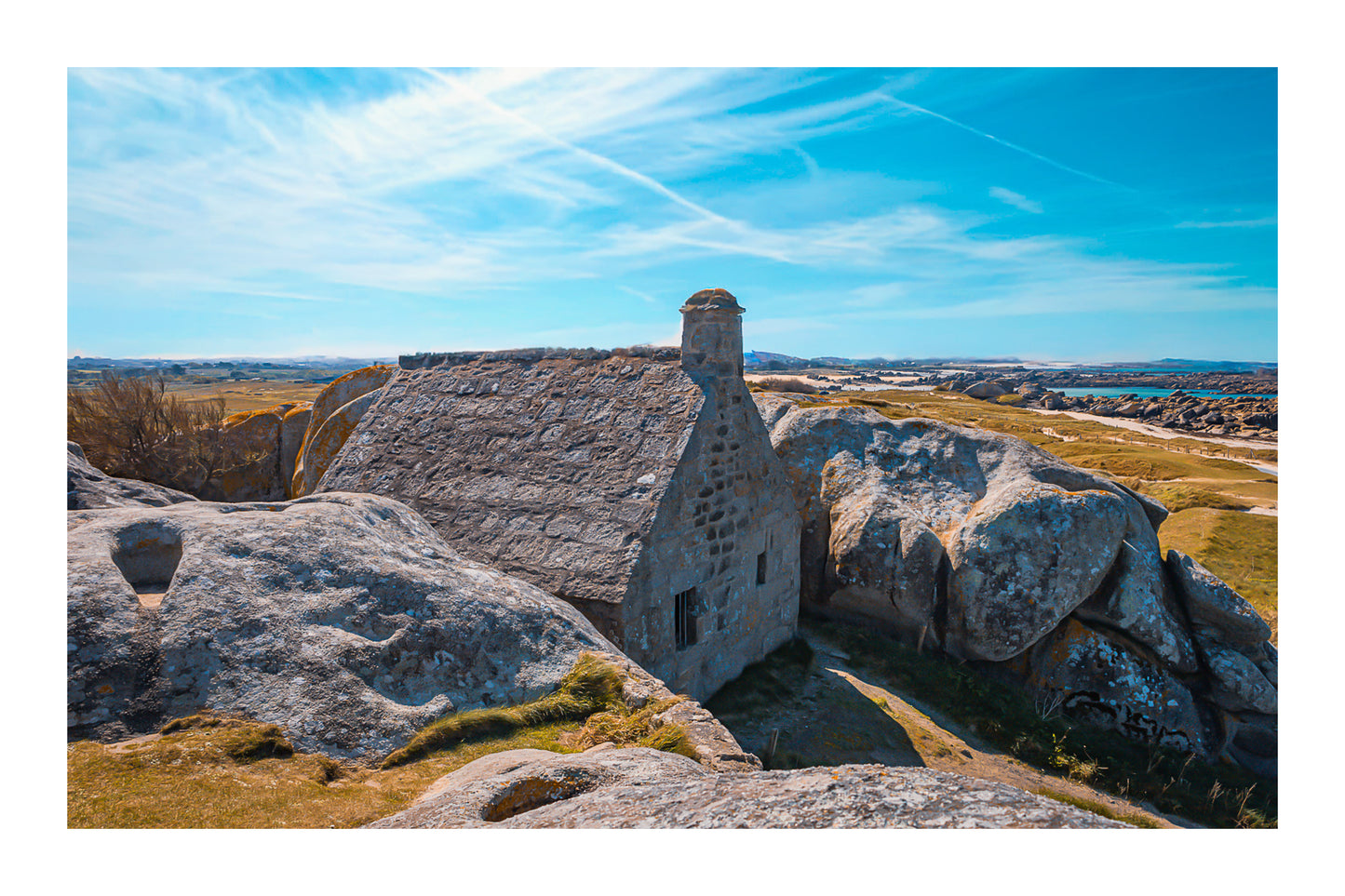 La maison emblématique de Meneham nichée entre deux énormes blocs de granit, vue d’ensemble, couleur avec bordure