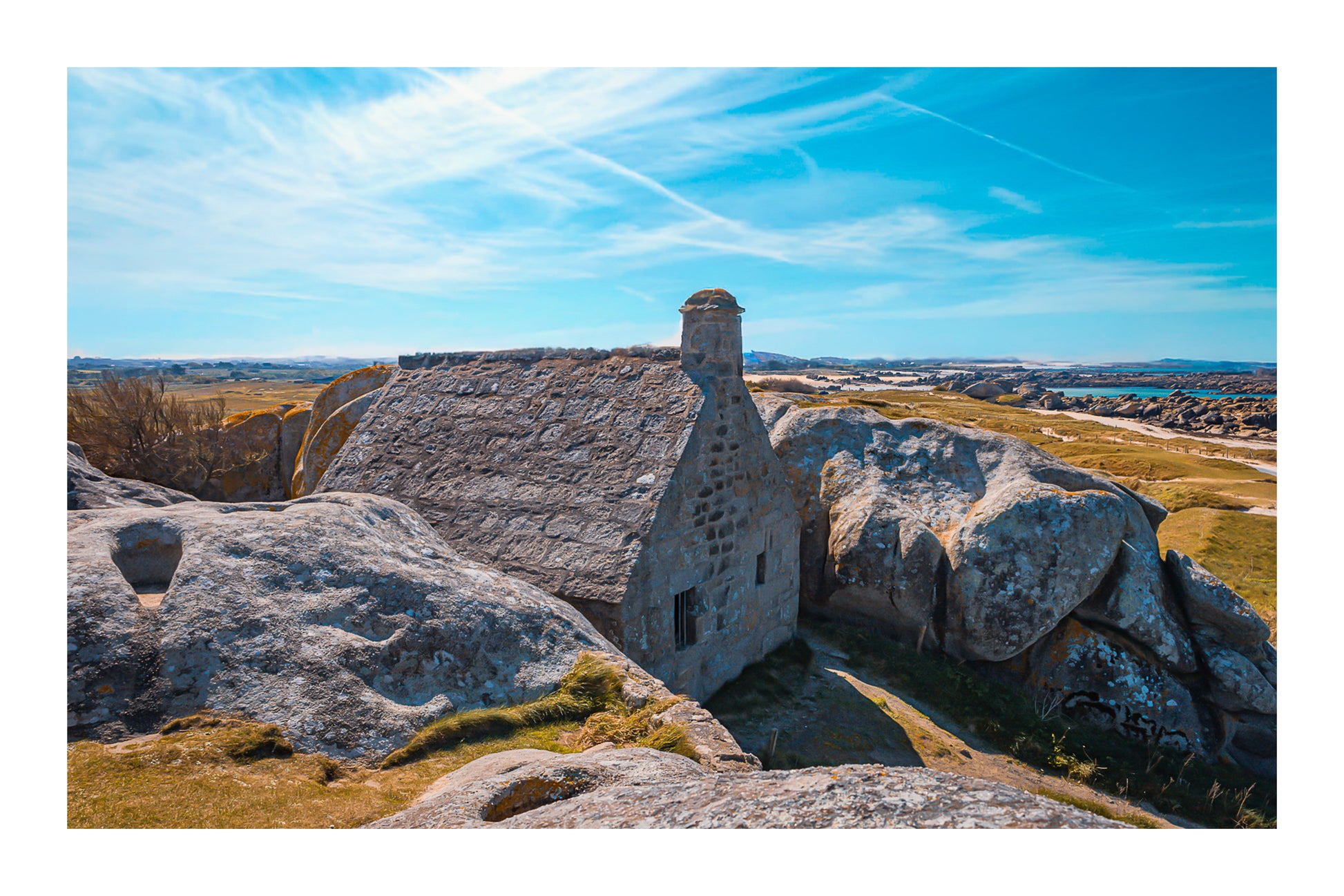 La maison emblématique de Meneham nichée entre deux énormes blocs de granit, vue d’ensemble, couleur avec bordure