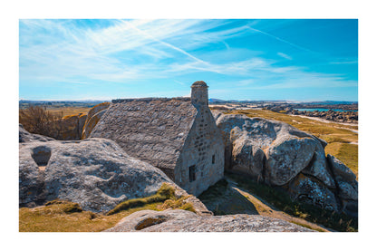La maison emblématique de Meneham nichée entre deux énormes blocs de granit, vue d’ensemble, couleur avec bordure