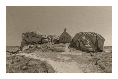 Façade de la maison des gardes encadrée par deux rochers monumentaux, Meneham (Kerlouan), traitement sepia avec bordure