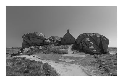 Façade de la maison des gardes encadrée par deux rochers monumentaux, Meneham (Kerlouan), noir et blanc avec bordure