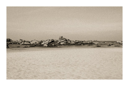 Grande plage claire avec rochers épars et ligne d’horizon marine, ambiance sépia vintage avec bordure à Meneham