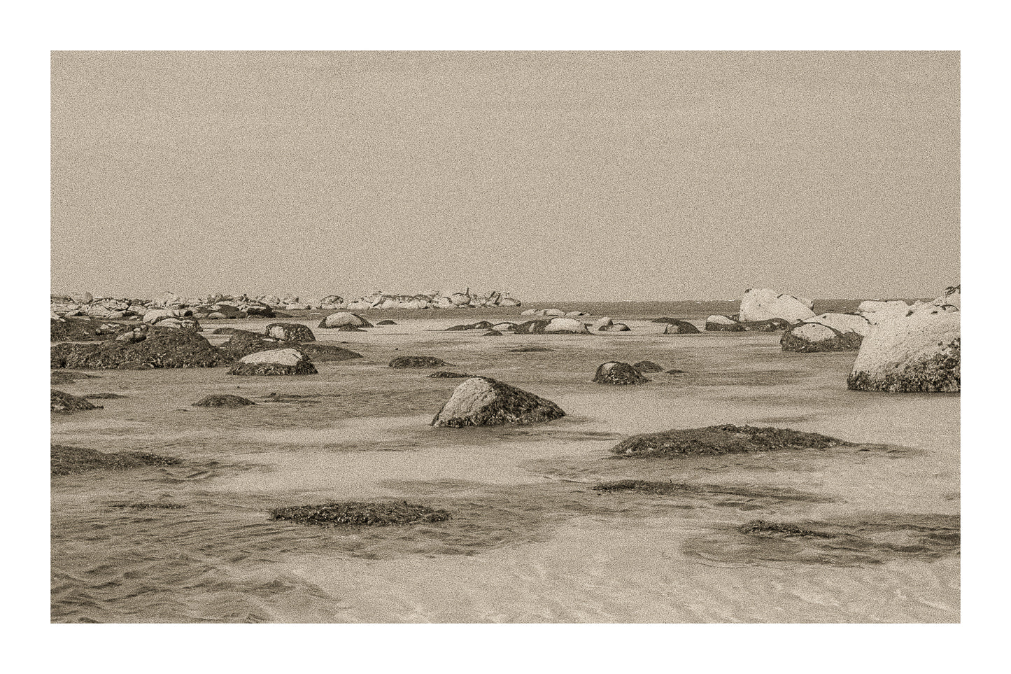 Rochers et laisses de mer à marée basse sur sable clair, rendu ancien sépia avec bordure, site de Meneham en Bretagne