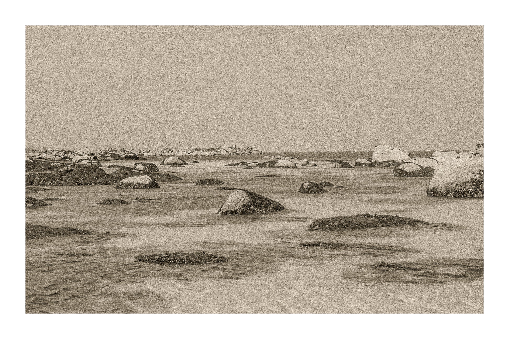 Rochers et laisses de mer à marée basse sur sable clair, rendu ancien sépia avec bordure, site de Meneham en Bretagne