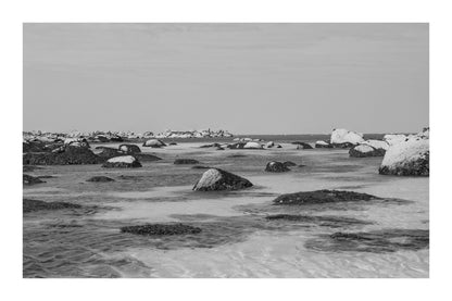 Rochers et laisses de mer à marée basse sur sable clair, noir et blanc avec bordure, site de Meneham en Bretagne
