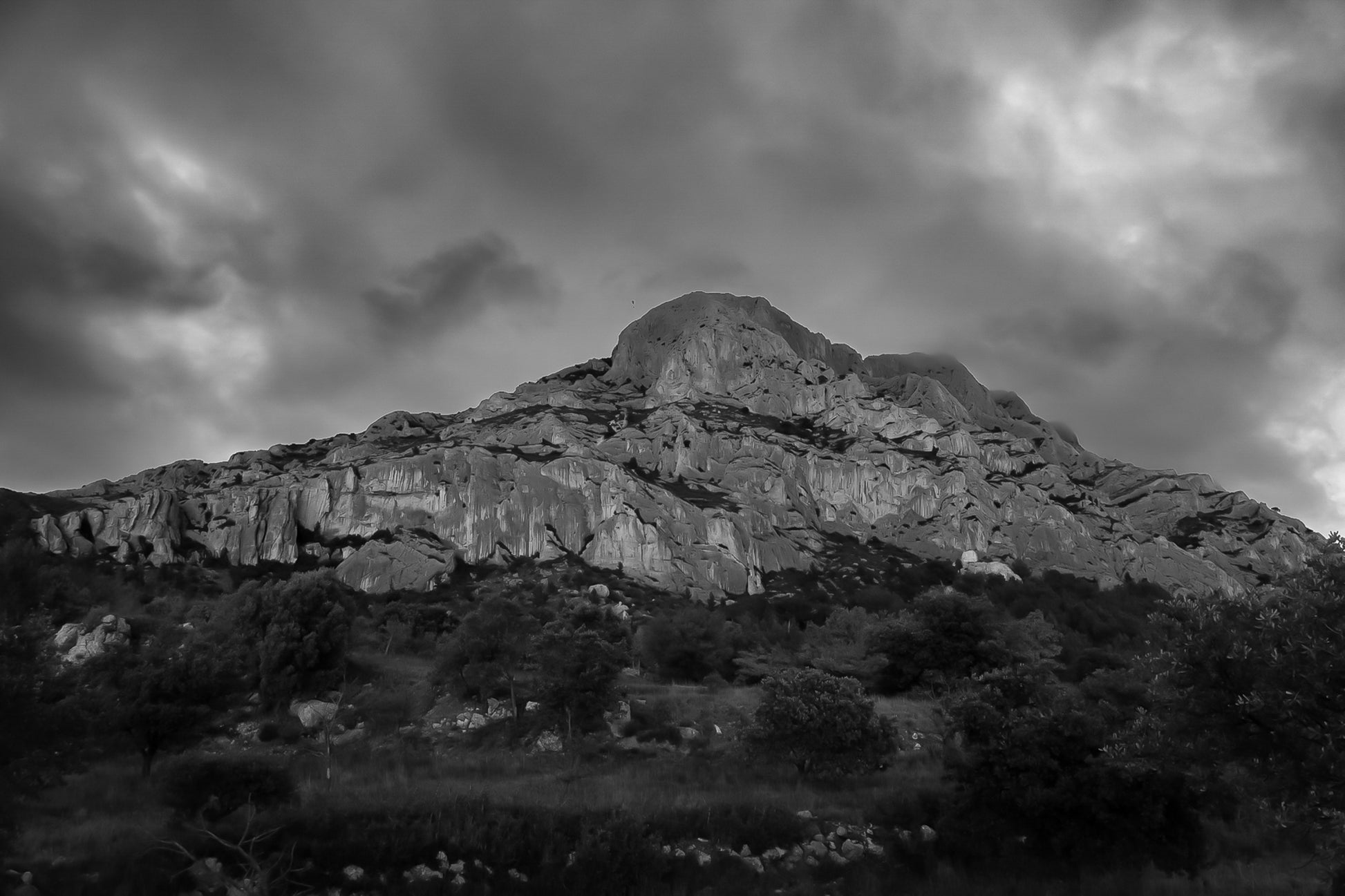 Montagne Sainte-Victoire sous un ciel d’orage vert et violet, vue depuis le pied de la falaise, noir et blanc