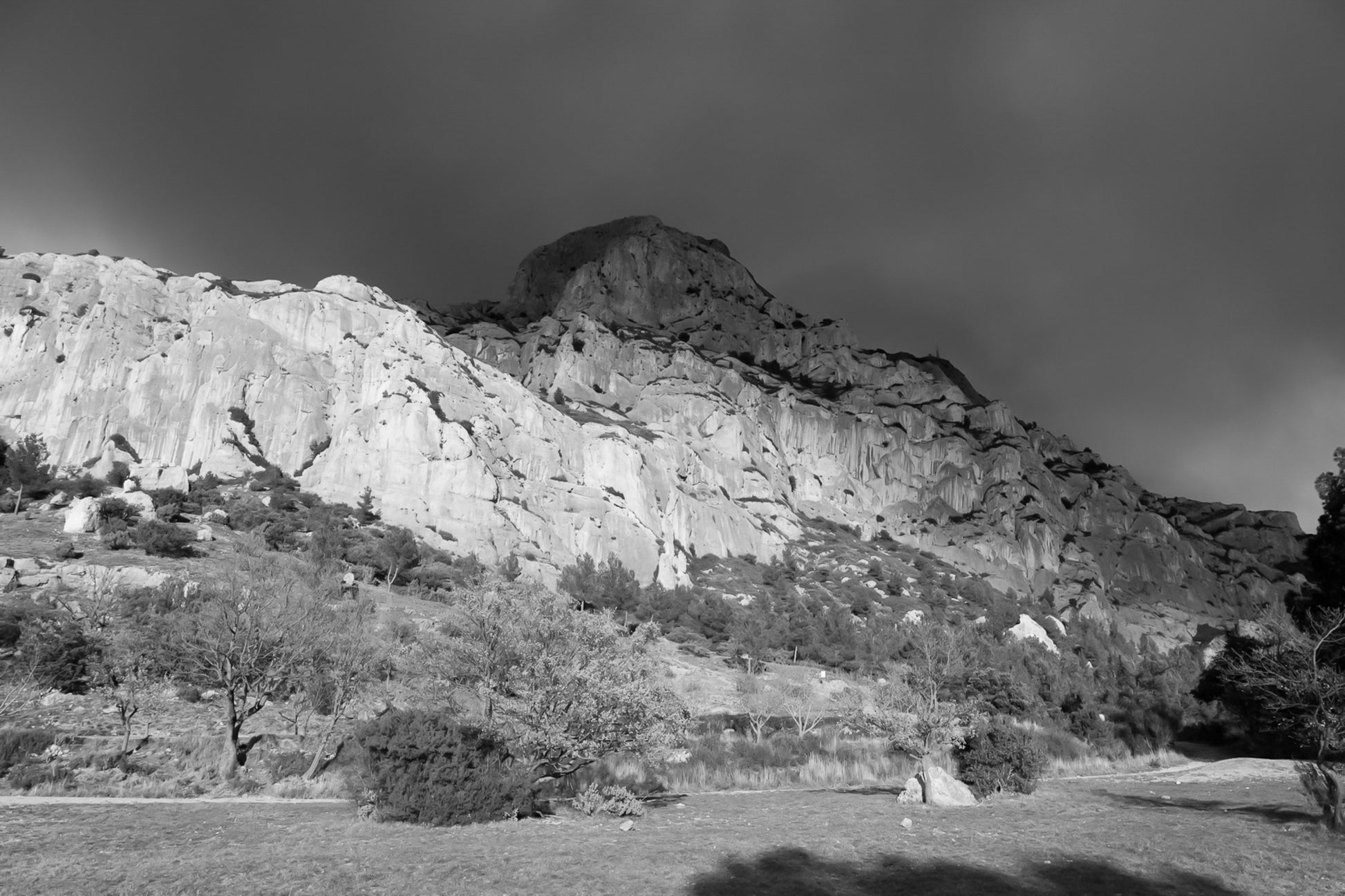 Falaise de la Sainte-Victoire dorée par le soleil avec gros nuages noirs au-dessus, noir et blanc