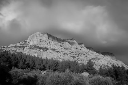 Crête de la Sainte-Victoire baignée de lumière dorée sous un ciel de nuages violets, noir et blanc