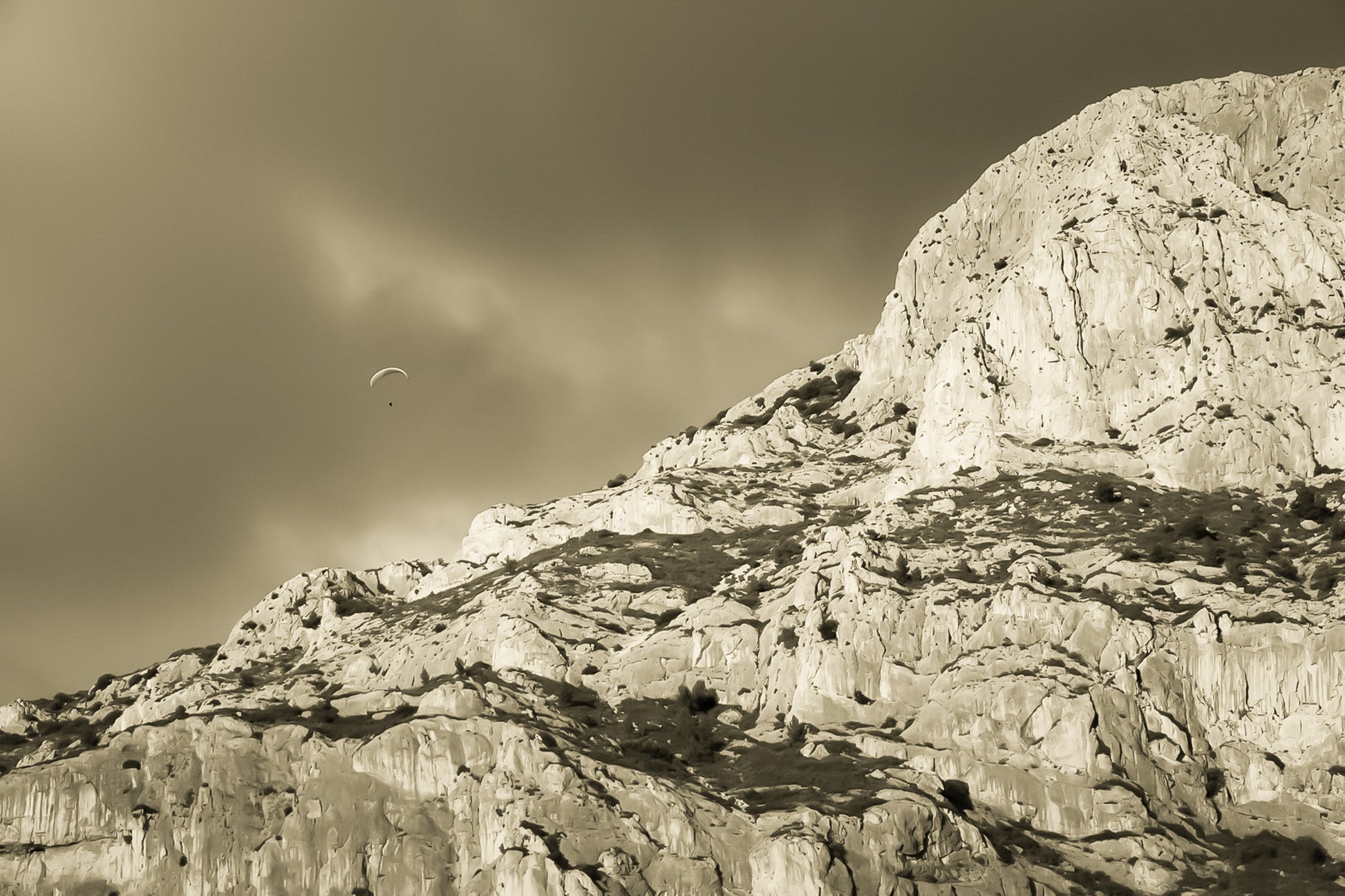 Parapente dans le ciel sombre au-dessus des falaises claires de la Sainte-Victoire, vintage