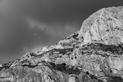 Parapente dans le ciel sombre au-dessus des falaises claires de la Sainte-Victoire, noir et blanc