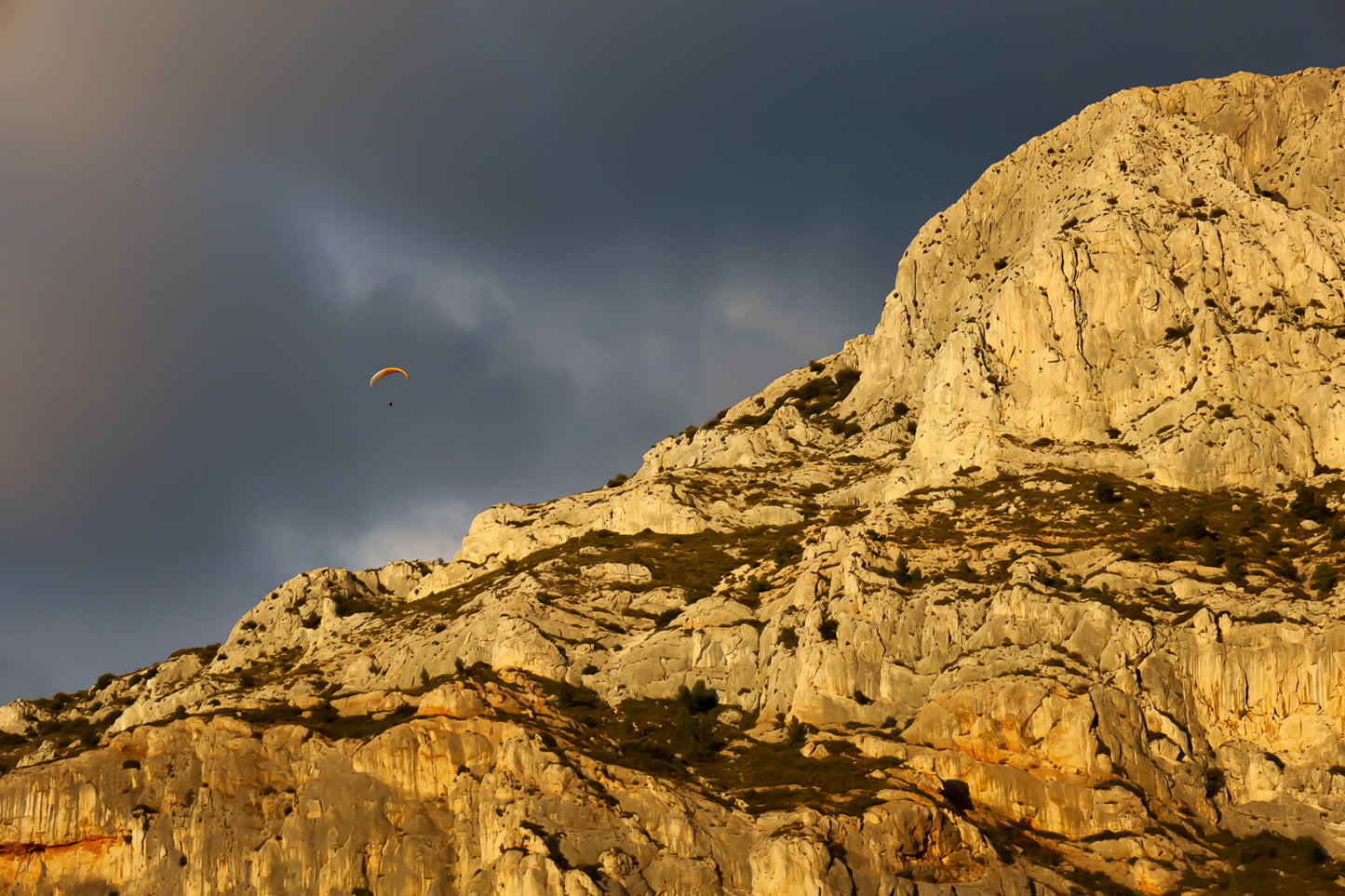 Parapente dans le ciel sombre au-dessus des falaises claires de la Sainte-Victoire