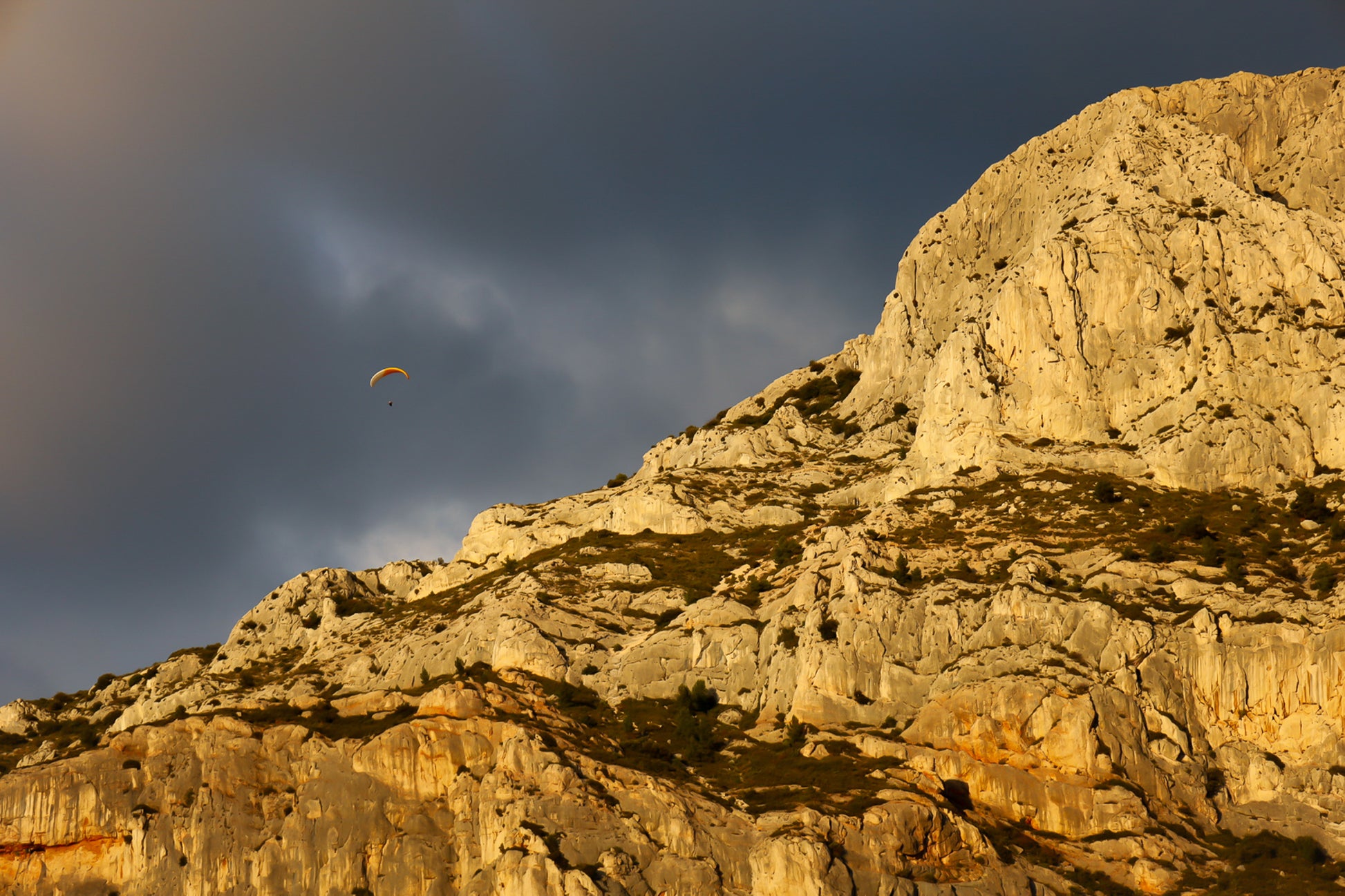 Parapente dans le ciel sombre au-dessus des falaises claires de la Sainte-Victoire
