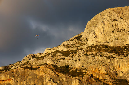 Parapente dans le ciel sombre au-dessus des falaises claires de la Sainte-Victoire