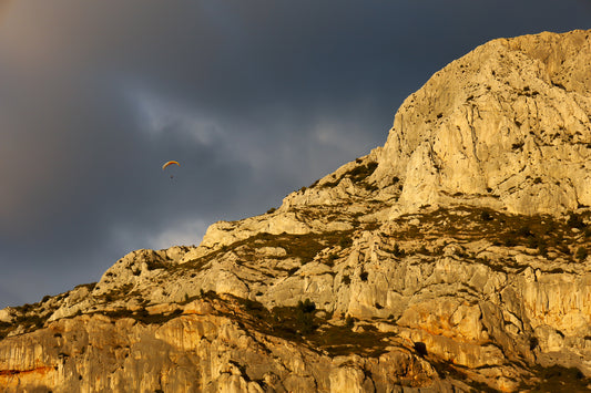 Parapente dans le ciel sombre au-dessus des falaises claires de la Sainte-Victoire