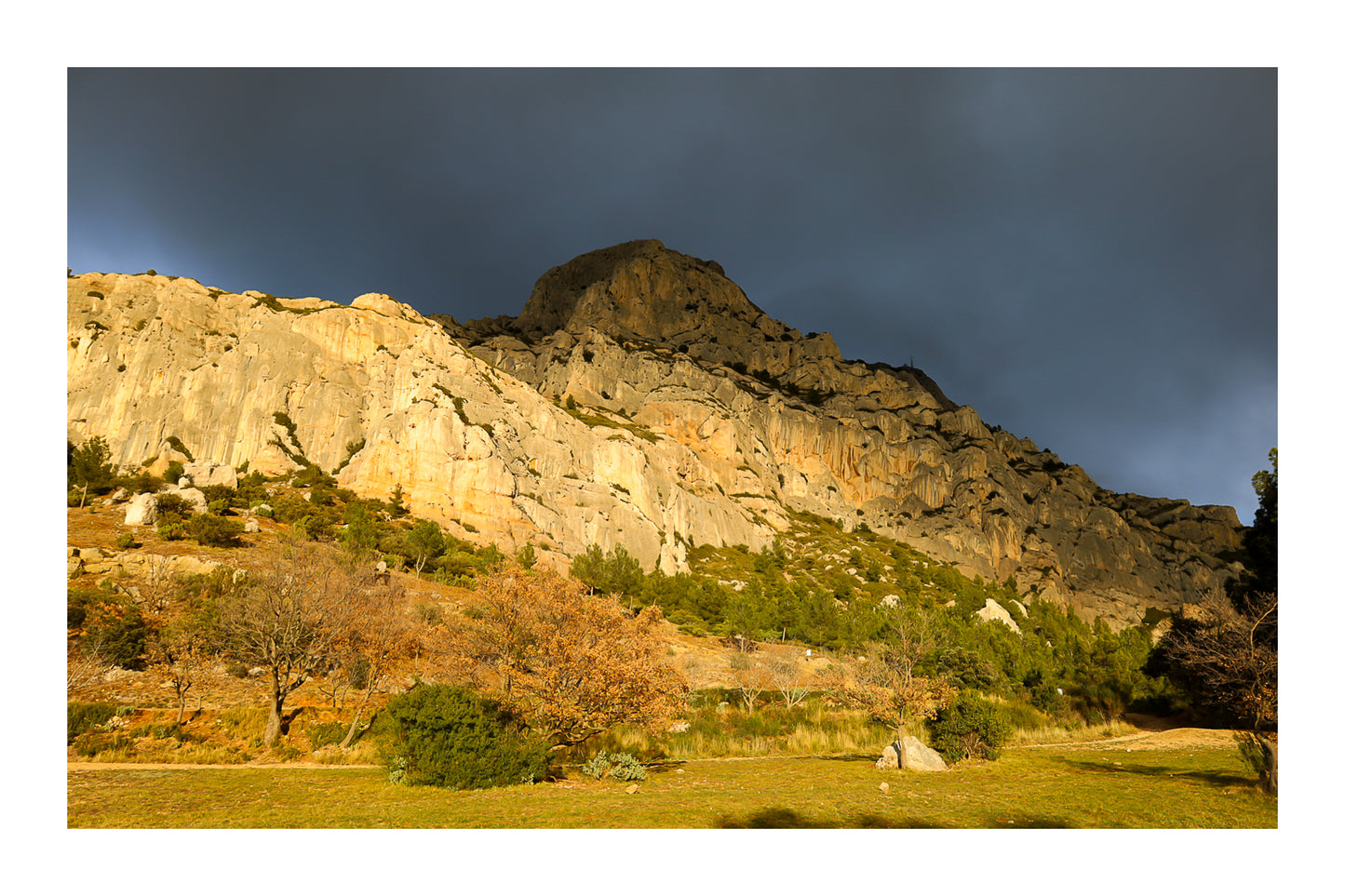 Falaise de la Sainte-Victoire dorée par le soleil avec gros nuages noirs au-dessus avec bordure